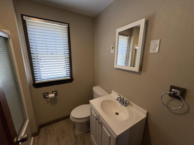 full bathroom featuring toilet, wood finished floors, a shower, baseboards, and vanity