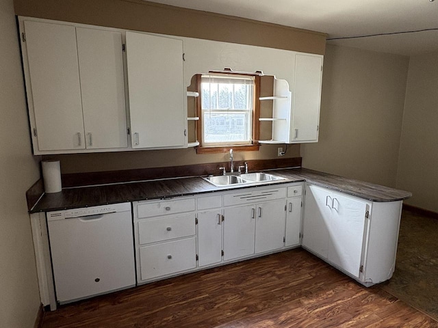 kitchen with dark countertops, white cabinetry, a sink, and white dishwasher