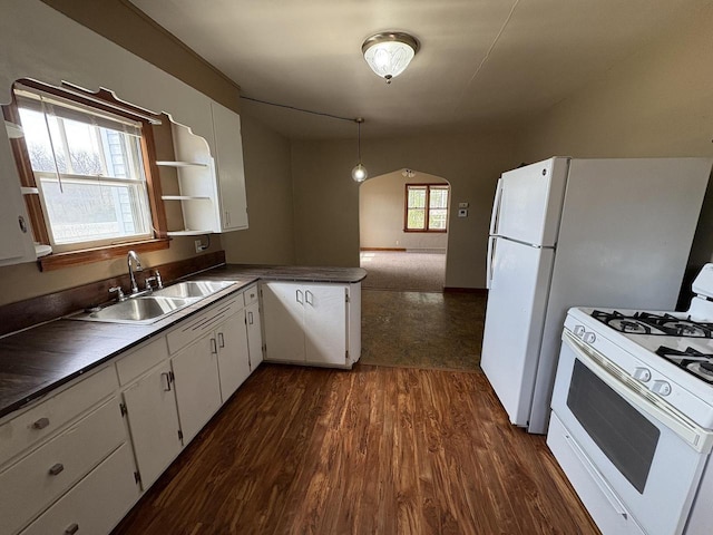 kitchen featuring arched walkways, white appliances, white cabinets, and a sink