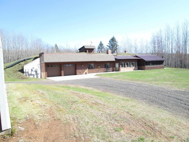 view of front facade with gravel driveway, a chimney, a front lawn, and an attached garage