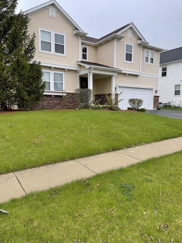 view of front of home with driveway, brick siding, a garage, and a front yard