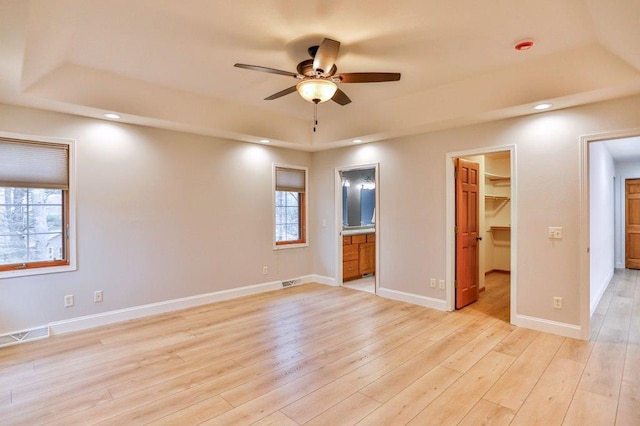 4109 Oak Ter, Weston, WI 54476 - unfurnished bedroom featuring a walk in closet, visible vents, light wood-style flooring, and a raised ceiling