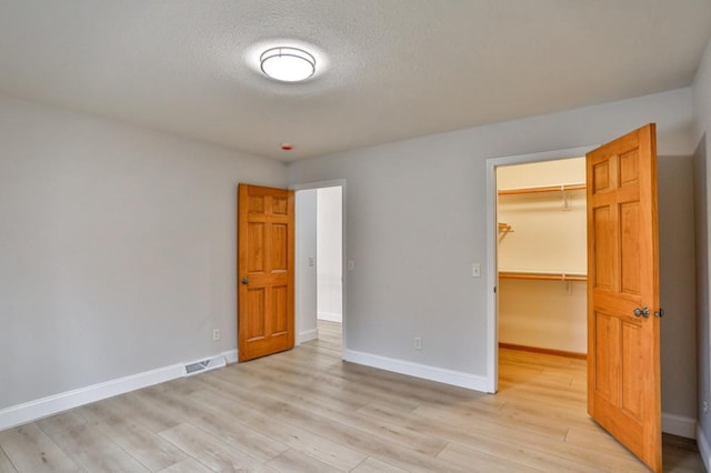 4109 Oak Ter, Weston, WI 54476 - unfurnished bedroom featuring a walk in closet, light wood-style flooring, baseboards, and a closet