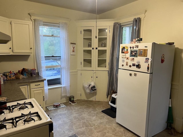 kitchen featuring white cabinetry, white appliances, dark countertops, and plenty of natural light