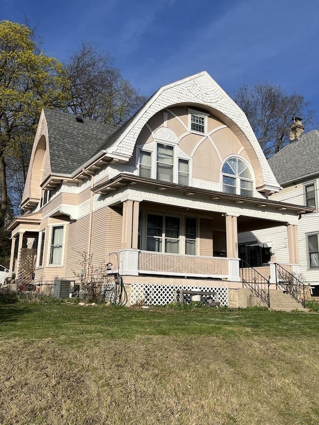 view of front of home with a porch, a shingled roof, a front lawn, and central air condition unit