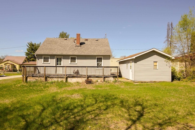 back of property with a chimney, a yard, and a wooden deck