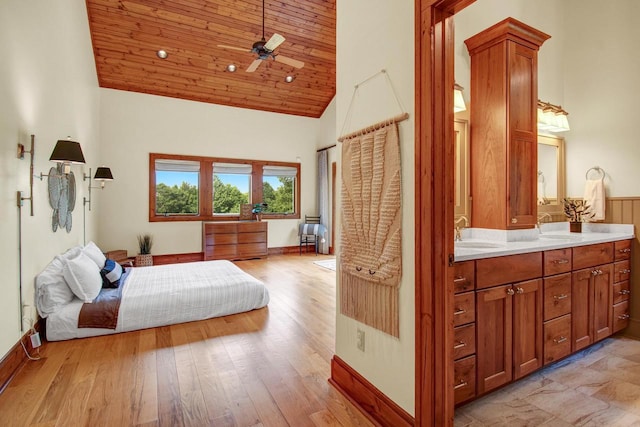 bedroom with light wood-type flooring, wood ceiling, high vaulted ceiling, and a sink