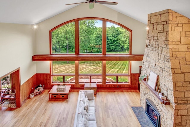 living room with a fireplace, ceiling fan, a wainscoted wall, and wood finished floors