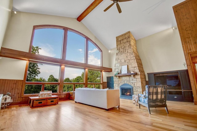 living area featuring wood-type flooring, high vaulted ceiling, a fireplace, ceiling fan, and beamed ceiling