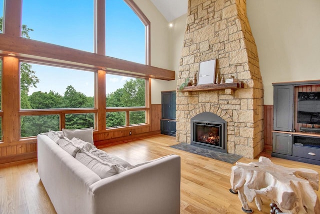 living room with a wainscoted wall, a fireplace, a high ceiling, and wood finished floors