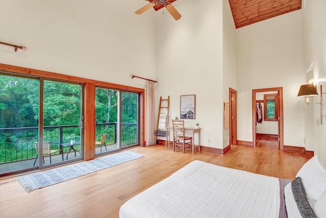 bedroom with wood finished floors, high vaulted ceiling, and access to exterior