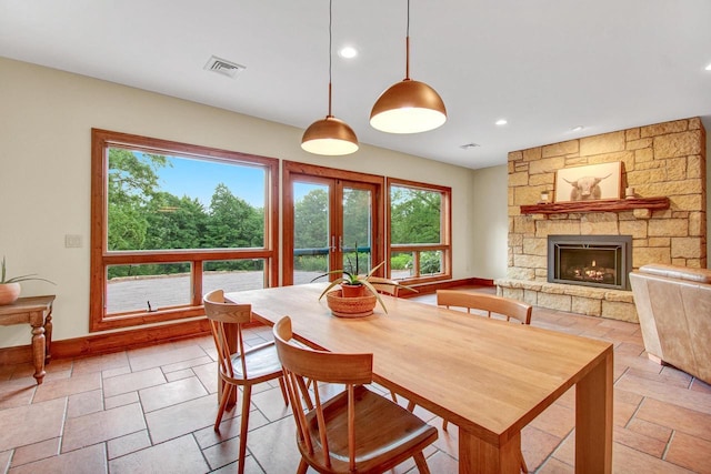 dining area with stone tile floors, a stone fireplace, french doors, and recessed lighting