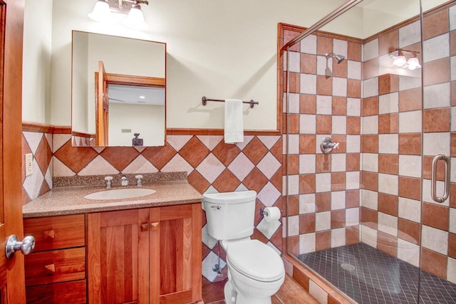 bathroom featuring a shower stall, vanity, toilet, and a wainscoted wall