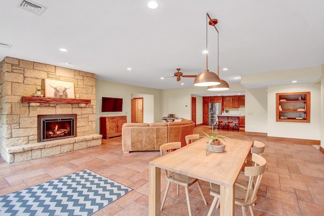 dining area with a ceiling fan, a fireplace, stone tile flooring, visible vents, and recessed lighting