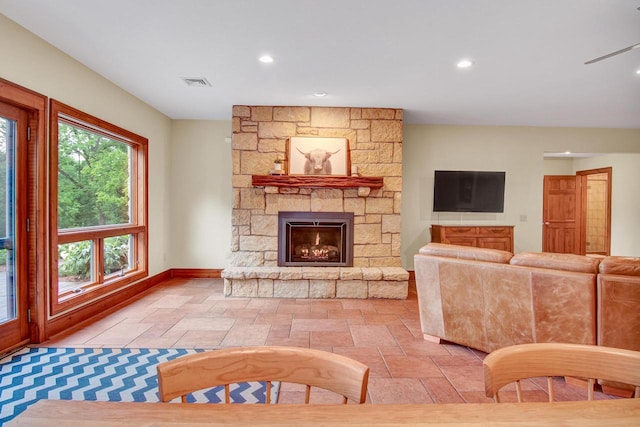 living area with visible vents, recessed lighting, stone tile floors, baseboards, and a stone fireplace