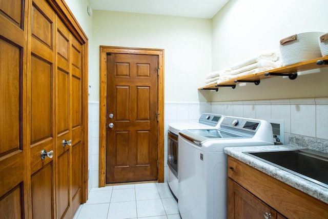 washroom featuring light tile patterned floors, tile walls, washer and dryer, and a wainscoted wall