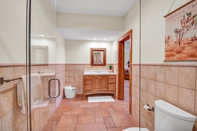 bathroom featuring tile walls, toilet, wainscoting, and a stall shower