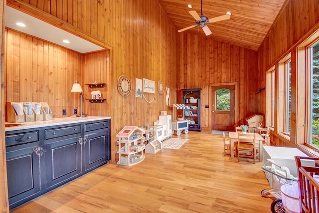 sitting room with ceiling fan, wood walls, a healthy amount of sunlight, and high vaulted ceiling