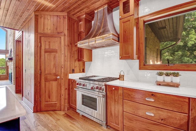 kitchen featuring wood ceiling, plenty of natural light, custom exhaust hood, and designer range