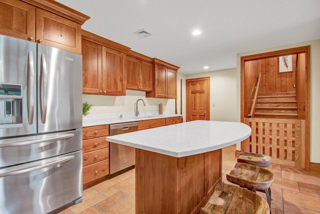 kitchen featuring stainless steel appliances, recessed lighting, brown cabinetry, a sink, and light countertops