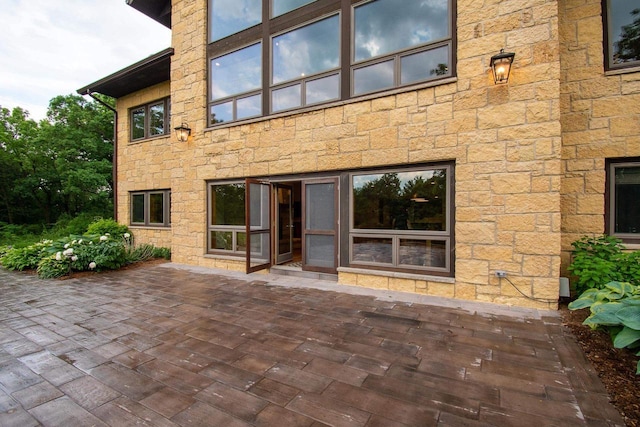 back of house with stone siding and a patio area