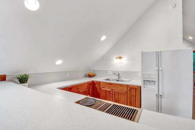 kitchen with a sink, white fridge with ice dispenser, recessed lighting, vaulted ceiling, and light countertops