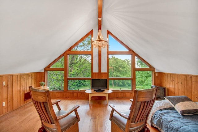 interior space with a chandelier, wood walls, lofted ceiling with beams, and light wood-style floors