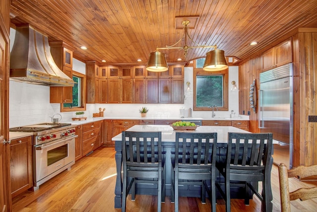 kitchen with range hood, wood ceiling, a kitchen breakfast bar, high quality appliances, and light countertops