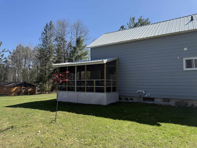 back of house featuring a yard, metal roof, and a sunroom