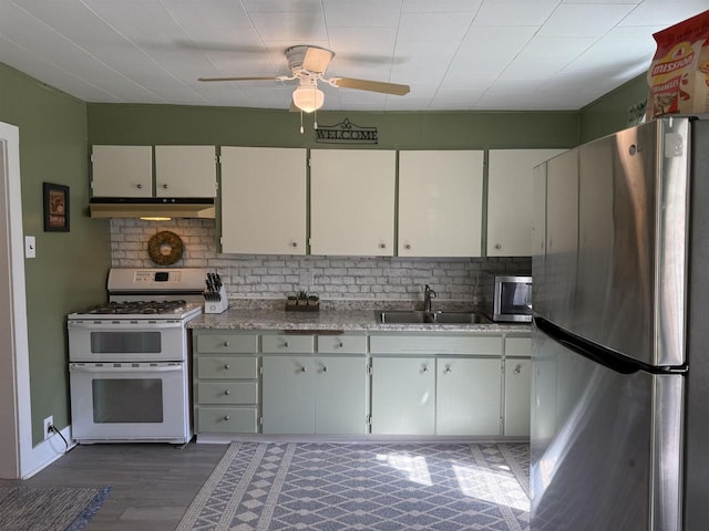 kitchen featuring a sink, ceiling fan, backsplash, under cabinet range hood, and appliances with stainless steel finishes