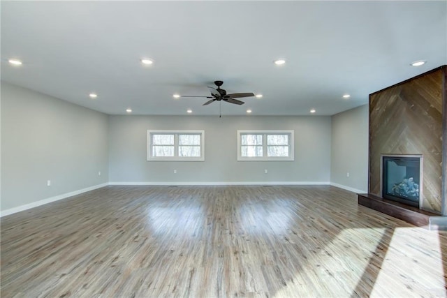 unfurnished living room featuring wood finished floors, recessed lighting, a fireplace, ceiling fan, and baseboards