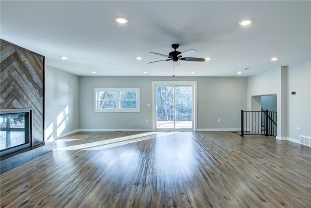 unfurnished living room with wood finished floors, a ceiling fan, visible vents, baseboards, and recessed lighting