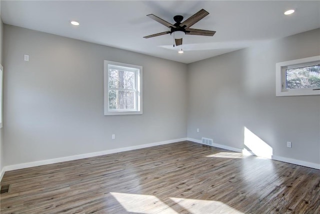 empty room featuring wood finished floors, visible vents, baseboards, and recessed lighting