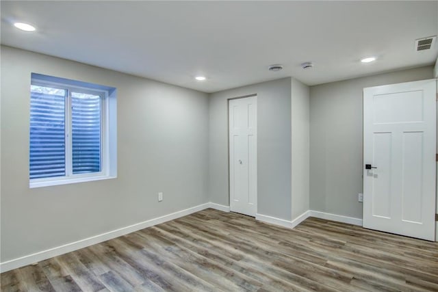 unfurnished room with wood finished floors, baseboards, visible vents, and recessed lighting