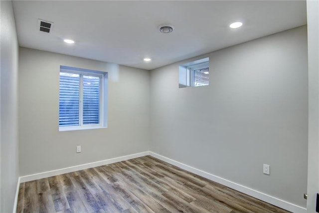 basement with a wealth of natural light, visible vents, wood finished floors, and baseboards