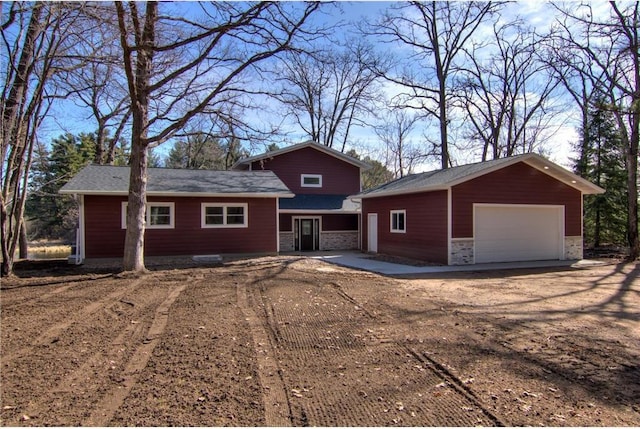 view of front of home featuring stone siding, a detached garage, and an outbuilding