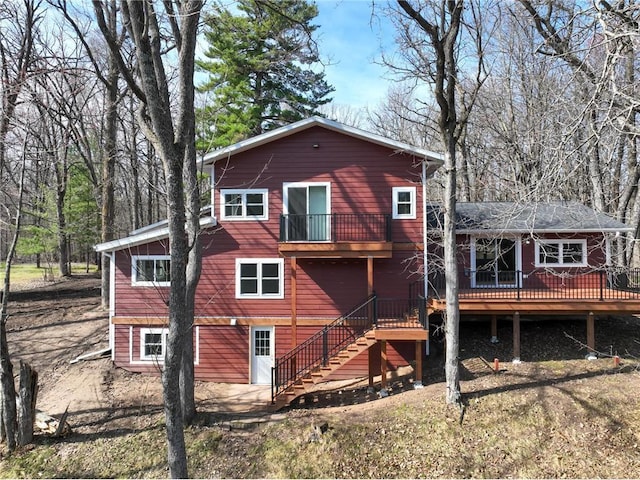 back of property featuring a balcony, stairs, and a deck