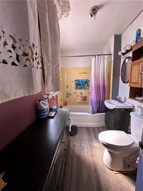 full bathroom featuring shower / bath combo with shower curtain, toilet, wood finished floors, and vanity
