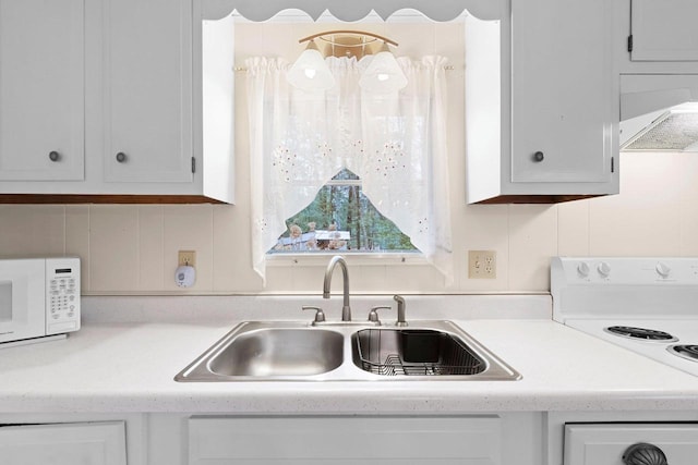 kitchen with a sink, range hood, white cabinetry, white appliances, and light countertops