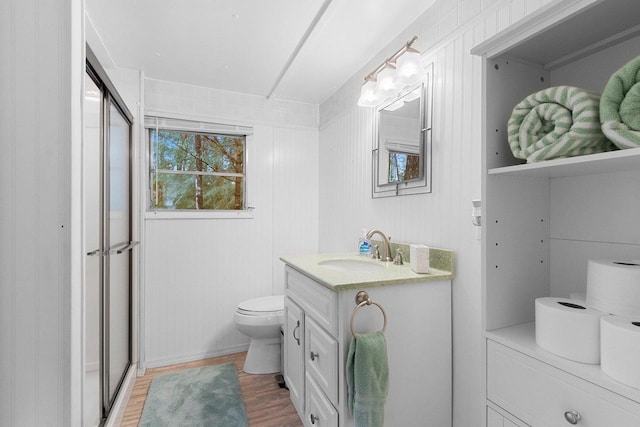full bath with a stall shower, vanity, toilet, and wood finished floors