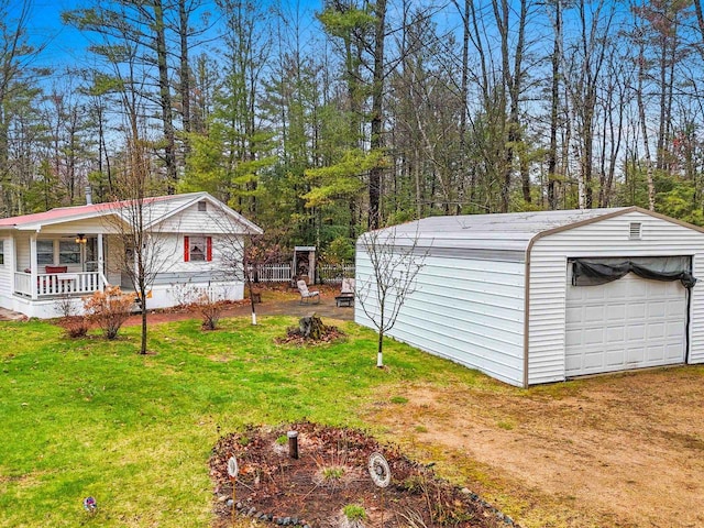 view of yard featuring driveway, an outdoor structure, covered porch, and a detached garage