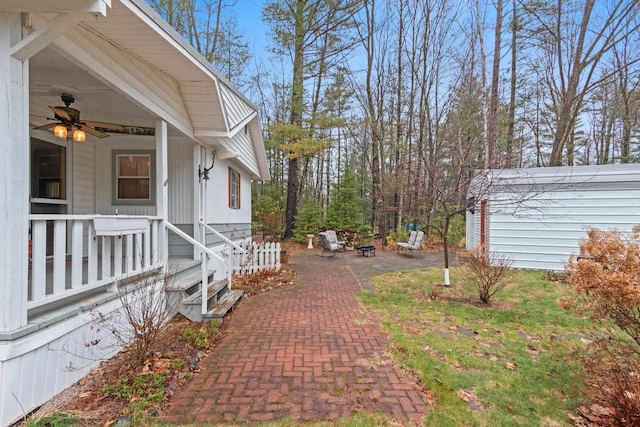 view of yard featuring a porch, a patio, a fire pit, and ceiling fan