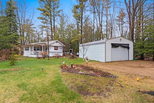 view of yard with a porch, dirt driveway, an outbuilding, and a detached garage