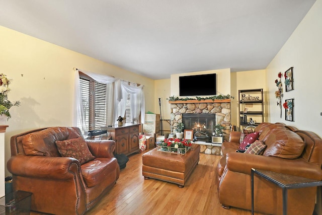 living area featuring light wood finished floors and a stone fireplace