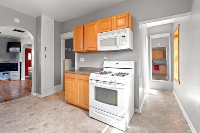 kitchen featuring dark countertops, visible vents, baseboards, arched walkways, and white appliances