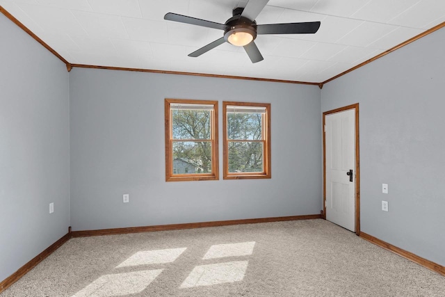 carpeted empty room with crown molding, baseboards, and a ceiling fan
