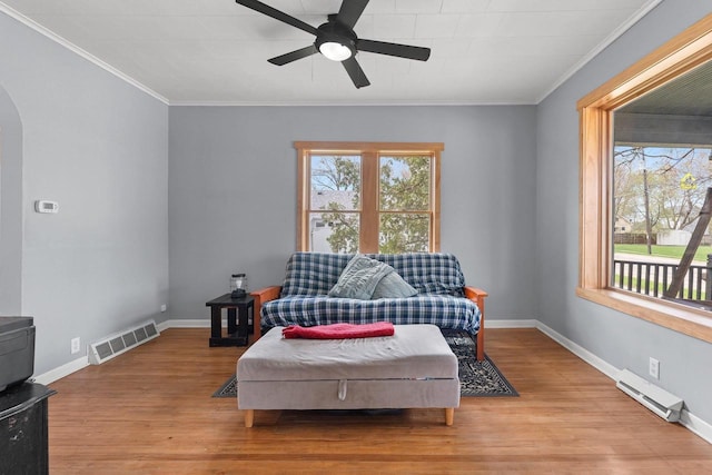 sitting room with light wood-type flooring, visible vents, a ceiling fan, and arched walkways
