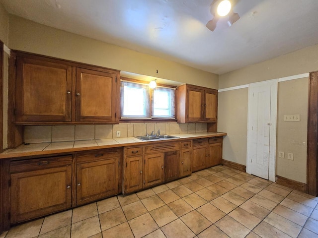 5535 N 40th St, Milwaukee, WI 53209 - kitchen featuring light tile patterned floors, brown cabinets, a sink, tile counters, and decorative backsplash