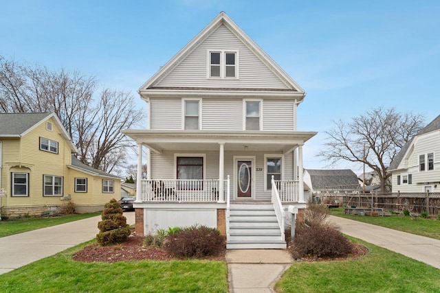 traditional style home featuring a porch, fence, and a front yard