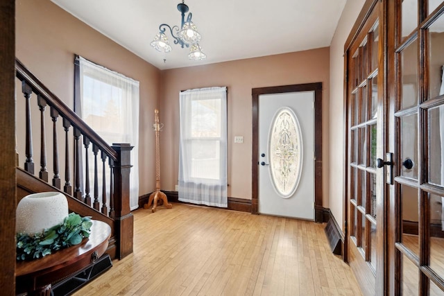 entryway featuring light wood finished floors, stairs, baseboards, and french doors